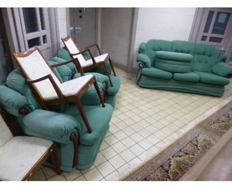 A GREEN UPHOLSTERED THREE PIECE SUITE, with wood trim, comprising three seater settee, two armchairs and a pouffe (4)