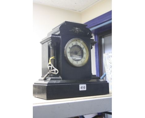 A BLACK SLATE MANTEL CLOCK, having architectural top with mask pediment over Arabic numerals chapter ring, corinthian column 