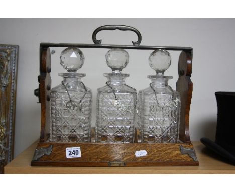 A THREE BOTTLED TANTALUS, Betjemanns patent, with three bottle labels 'Gin', 'Whisky' and 'Brandy' (no key)