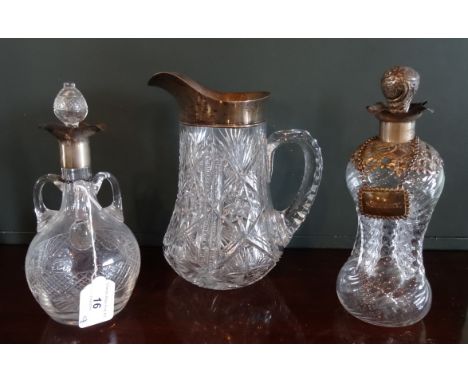 A cut glass crystal water jug, having silver mount, together with two late 19th/early 20th century decanters, each having sil