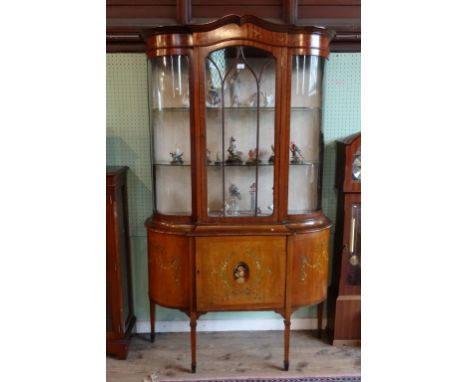 An early 20th century display cabinet, the single astral glazed door flanked by curved glazed sides, over single cupboard doo