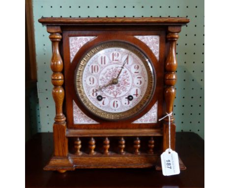 An early 20th century oak cased mantle clock the ceramic dial having floral decoration, bearing Arabic numerals (29cm).