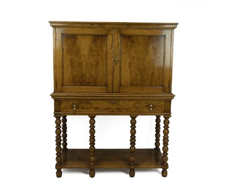 Contemporary oak drinks cabinet on stand, with two panelled doors revealing a shaped single shelf and central brush slide abo