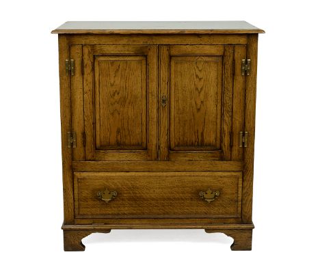 Contemporary oak panelled, two door oak cabinet; the doors enclosing a single shelf above a single drawer base raised on brac