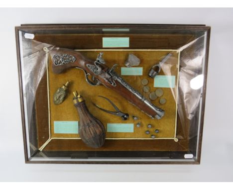 Framed in a glass case reproduction Flintlock pistol, powder flask, bullet mould, wad cutter &amp; flint. 22.5" by 17"