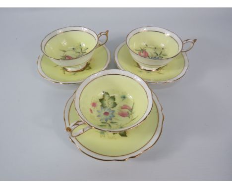 Three Paragon china cups and saucers, yellow and white with floral decoration inside the bowl and on the saucers.