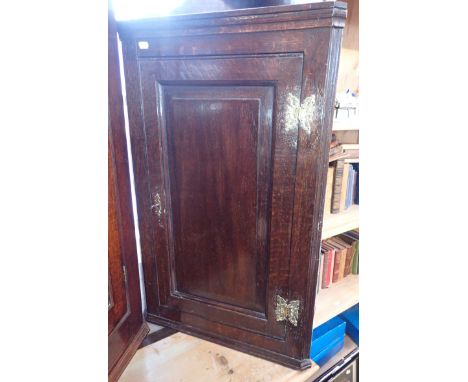 A SMALL GEORGE III OAK HANGING CORNER CUPBOARD with shaped top and shelf over a single door