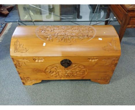 A DOMED TOP CAMPHOR WOOD TRUNK carved to top and sides with floral vignettes
