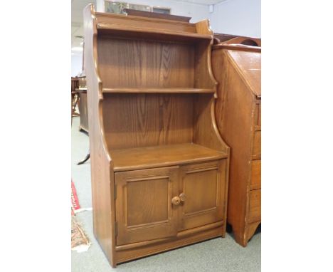 AN ERCOL ELM WATERFALL BOOKCASE 111cm high x 61cm wide x 31cm deep (label inside left door)