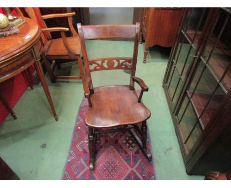 Circa 1860 an East Anglian elm knife back child's rocking chair with fretwork cross splat on ring turned fore legs joined by 
