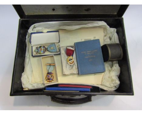 A leather case containing Masonic items, apron, lodge book, napkin ring and medals, including founder medal for Kentmere lodg