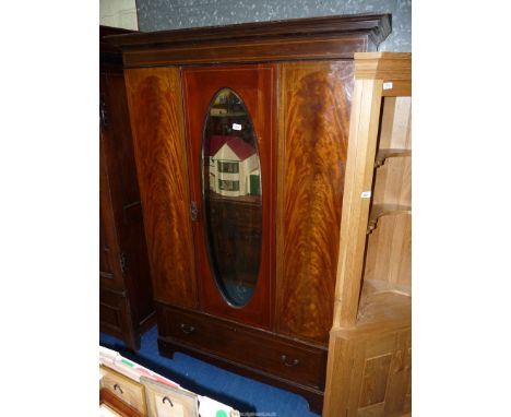 A flame Mahogany Wardrobe having an oval bevelled mirror to the door, a deep hat drawer below and with light and darkwood str
