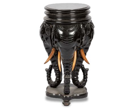 A 19TH CENTURY EBONISED JARDINIÈRE STAND the circular top raised on elephant mask supports joined by a shelf under tier, pale