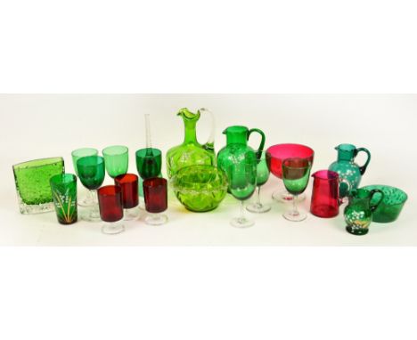 A collection of green and cranberry coloured glass including four jugs and a beaker and bowl decorated with white enamel flor