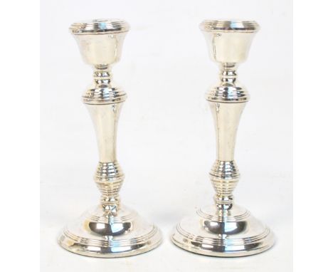 A pair of Elizabeth II hallmarked silver candlesticks with bell shaped sconces raised on tapering knopped stems to spreading 