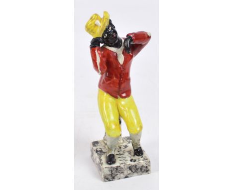 An unusual Staffordshire figure of a seated black man in a yellow hat on a square mottled base, height 18cm. CONDITION REPORT