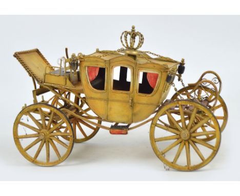 A vintage tin plate model of a stagecoach including crown finial, painted gold with red window curtains, length 42cm, height 