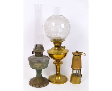 A brass oil lamp with chimney and globular etched shade, height 57cm, another example with chimney and a miner's light with a