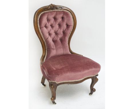 A late Victorian carved walnut button upholstered salon chair raised on cabriole front legs.