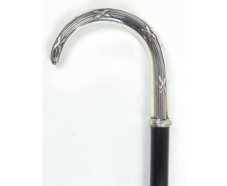 An ebonised walking stick with white metal handle with rib and ribbon moulded decoration, length 89cm.