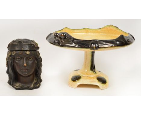 A ceramic Art Nouveau comport in cream crackle type glaze with dark brown rim, with scrolls and fruits, raised on a central s