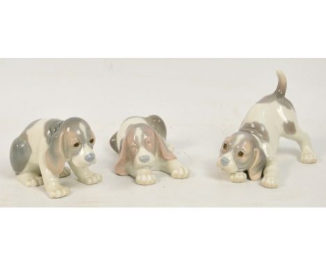 Three Lladro figures of puppies sitting, sleeping or playing. CONDITION REPORT: All three in good condition, although one has