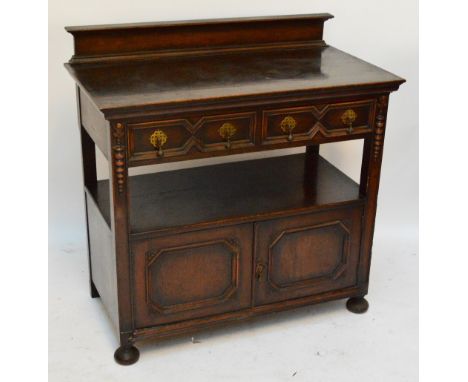 An early 20th century oak buffet with geometric pattern, the two drawers above a shelf above two hinged doors raised on bun f