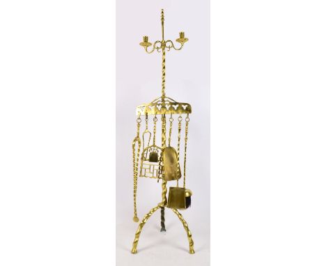 An unusual brass companion set of upright form with central twisted column supporting two candle sconces above various tools 