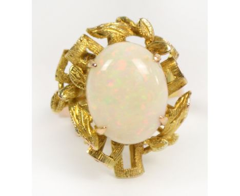 An 18ct yellow gold opal ring, the large central oval opal within a textured pierced frame, size L.