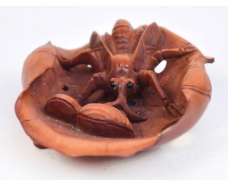 A Chinese carved boxwood netsuke of a bug on a lily pad, diameter 6cm (small chips to rim).