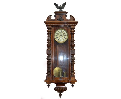 A c.1900 Vienna style mahogany wall clock with turned and carved pilasters, the cream enamel circular chapter ring with Roman