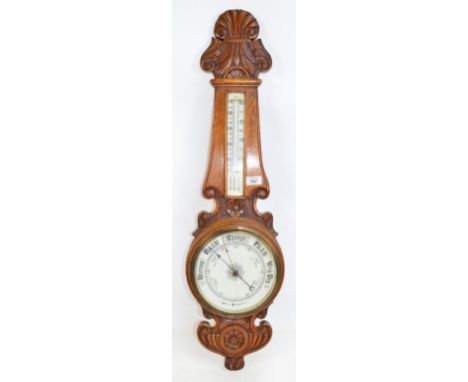 A late Victorian carved oak aneroid barometer with floral detail to the case, height 92cm.