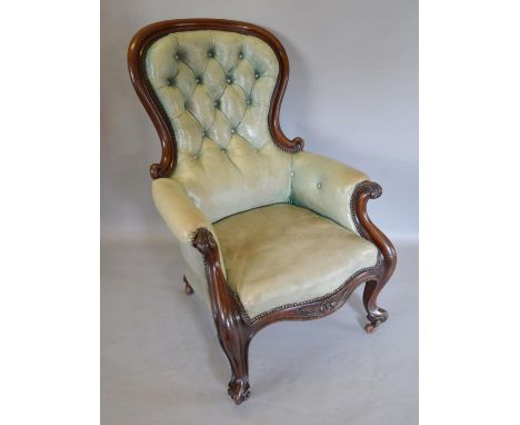 A Victorian Mahogany Green Leather Library Armchair with a button upholstered back above a serpentine seat with scroll arms, 