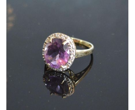 A Yellow Gold Amethyst And Diamond Ring set with a large oval amethyst surrounded by diamonds claw set 