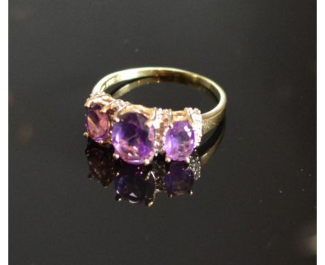 A Yellow Gold Amethyst And Diamond Set Ring with three oval amethyst interspaced with diamonds within a pierced setting 