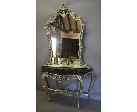 A French Silvered Console Table with a large shaped mirror above a marble top, the base with a scroll frieze, raised upon cab