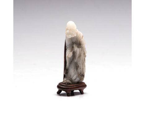 A CHINESE CELADON JADE CARVING OF A SAGE, LATE 19TH/EARLY 20TH CENTURY carved in profile, the sauntering figure dressed in he