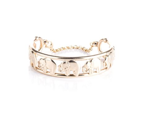 A YELLOW GOLD ELEPHANT BANGLE the row of 7 9k yellow gold elephants between bars and finished with two oval cabochon sapphire