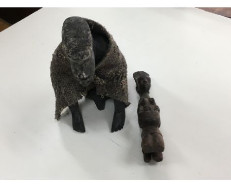 Two carved wooden figures, one is an old figure sat on a stool with a cloak and the other is a small figure of a female kneel