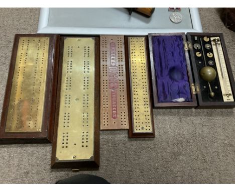 A converted gun stock cribbage board framed with additional military related items together with 4 vintage cribbage boards, c