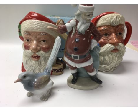 A Lladro figure in the form Father Christmas a Lladro bird and two Royal Doulton Father Christmas jugs .together with Nao fig