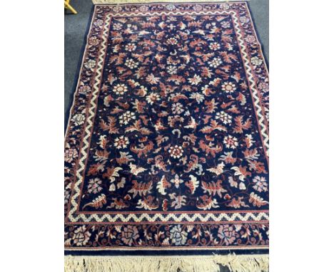 A fringed machine made Persian style carpet on blue ground  CONDITION REPORT: 171 cm x 244 cm