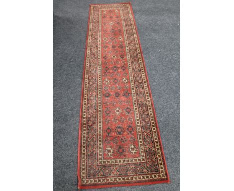 A woolen carpet runner on red ground  CONDITION REPORT: 68 cm x 270 cm.