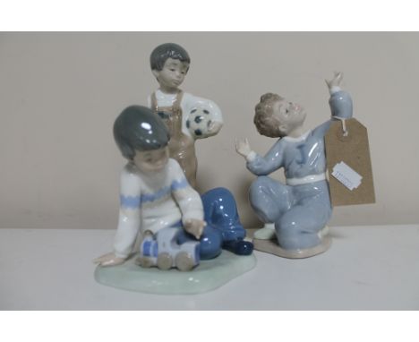 Three Nao figures; boy kneeling, boy with train and boy with football 