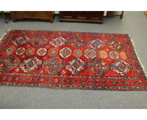 A Caucasian rug of geometric design on red ground, 170 cm x 307 cm  CONDITION REPORT: The carpet is in pretty good condition,