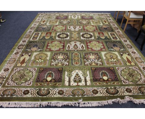 A machine made Persian design fringed carpet of compartmentalised design on green ground 