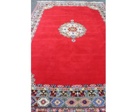 A fringed woolen Persian carpet on red ground with central medallion 440 cm x 295 cm. CONDITION REPORT: Light use and mostly 