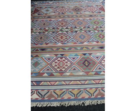 A fringed Kilim carpet on blue ground 301 cm x 246 cm. CONDITION REPORT: This is machine made.