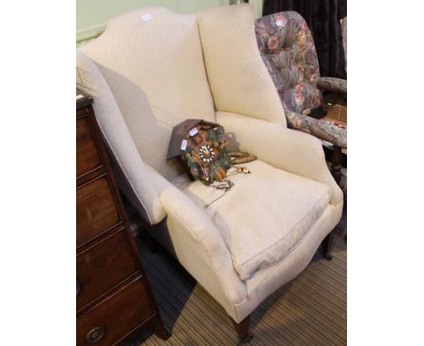 A GEORGIAN DESIGN WING BACKED ARMCHAIR all-over upholstered in old gold trellis pattern cotton, having feather filled squab c