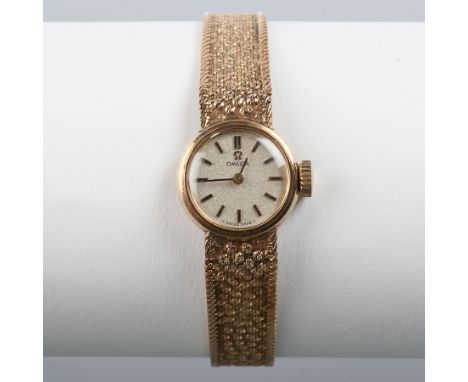 LADY'S NINE CARAT GOLD OMEGA WRISTWATCH WITH GOLD BRACELET STRAP the silvered dial with baton hour markers, in nine carat gol